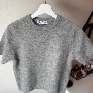 Grå stickad kortärmad tröja från Zara - Supermjuk grå stickad tröja från Zara med korta ärmar och rund halsringning. Storlek M men skulle säga att den passar en S