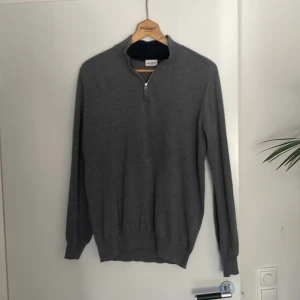Grå halvzip stickad tröja - Grå tröja från John Henric med halv dragkedja i halsen. Perfekt för lager-på-lager under kyliga dagar. Är storlek Medium.                                               Säljs för 500 kr