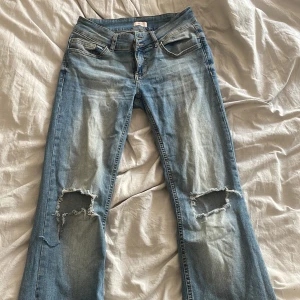 Ljusblå slitna jeans från Nelly - Ljusblå jeans från Nelly med slitningar och stora hål vid knäna. Klassisk femficksmodell med snygga detaljer på bakfickorna och knappstängning. Jeansen har en rak passform och är tillverkade i mjukt denimtyg.