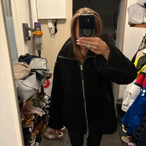 Svart teddyjacka med dragkedja från hm - Mysig svart teddyjacka med oversized passform och stor krage. Jackan har hel dragkedja framtill och långa ärmar. Perfekt för kalla dagar när du vill vara både varm och snygg. Enkel att matcha med olika outfits.