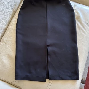 Svart pennkjol från Esprit - Snygg svart pennkjol från Esprit i klassisk modell med slits framtill. Kjolen är figurnära och passar perfekt till en stilren look. Tillverkad i ett mjukt och stretchigt material som ger en bekväm passform.