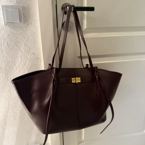 Väska - Säljer den här vinröda long strap pu bag från Gina tricot i den stora modellen. Den är aldrig använd. Det är färgen som heter ”lila” på hemsidan. Den är slutsåld på hemsidan.