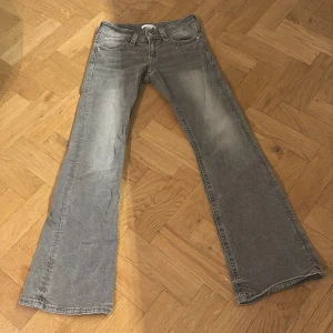 Grå bootcut jeans från Gina Tricot - Snygga grå jeans från Gina Tricot i storlek 152. Modellen har bootcut-ben och klassisk femficksdesign med knapp och dragkedja framtill. Jeansen är tillverkade i mjukt denimtyg och har en cool, tvättad look.