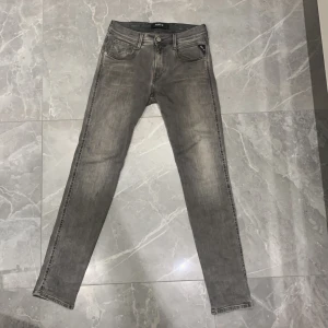 Replay Hyperflex grå jeans slim fit - Snygga Replay Hyperflex jeans i grå tvätt med klassisk femficksdesign och svarta detaljer på bakfickan. Jeansen har slim fit. Storleken är W29 L32.