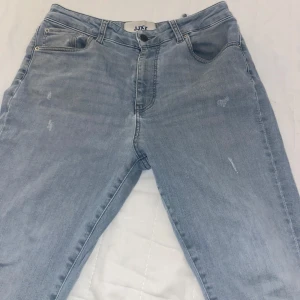 Ljusblå skinny high waist jeans - Snygga ljusblå skinny jeans från Jack & Jones med hög midja. Klassisk femficksmodell i stretchigt denimtyg, perfekt för dig som gillar en tight passform. Lätta slitningar framtill för en cool, avslappnad look.
