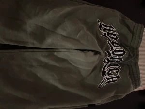 Gröna mjukisbyxor från Hoodrich S - Snygga gröna mjukisbyxor från Hoodrich i storlek S. Byxorna har elastisk midja med snörning och ett stort Hoodrich-tryck på ena benet. Mjukt material som är perfekt för chill och streetwear. Passformen är loose och färgen är mörkgrön.