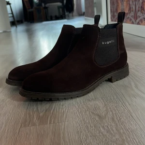 Bruna Chelsea boots från Bugatti - Snygga Chelsea boots från Bugatti i mörkbrunt mocka. Sparsamt använda. 