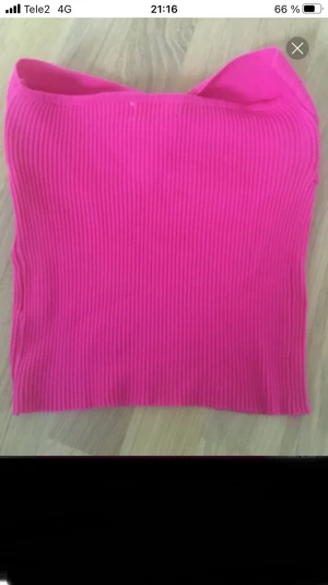 Ribbad rosa bandeau tubtopp - Säljer en snygg bandeau tubtopp i stark rosa färg. Toppen är ribbad och har en twistad detalj framtill som ger en cool look. Den är axelbandslös och har en tight passform som sitter perfekt. Perfekt för sommarens alla tillfällen!