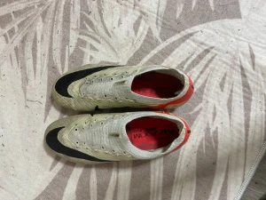 Nike Mercurial Air Zoom fotbollsskor elite  - Säljer ett par Nike Mercurial Air Zoom fotbollsskor i beige med svarta och röda detaljer. Skorna har en strömlinjeformad design med platt sula och rund tå, tillverkade i syntetmaterial för lätthet och snabbhet på planen. Den är elite 