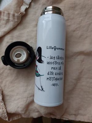 Lilla Gumman Termosmugg 0,4L - Snygg termosmugg med Lilla Gumman-motiv och rolig text. Vit färg, tryck och illustration i fint skick. Lock med trycköppning, insidan ser ren ut. Mindre yttre slitage syns, men överlag gott skick. Perfekt för kaffe eller te på språng.