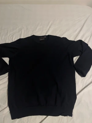 Marinblå  stickad tröja från Oscar Jacobson - Klassisk svart stickad tröja från Oscar Jacobson, tillverkad i Italien. Rund halsringning och ribbade muddar vid ärmslut och nederkant. Perfekt för dig som gillar stilrena och tidlösa plagg. Passar dig som vill ha en enkel men snygg look. Scick 8/10 då det finns lite tecken på användning men inget som stör hör av er vid funderingar. Priset är ej hugget i sten👍