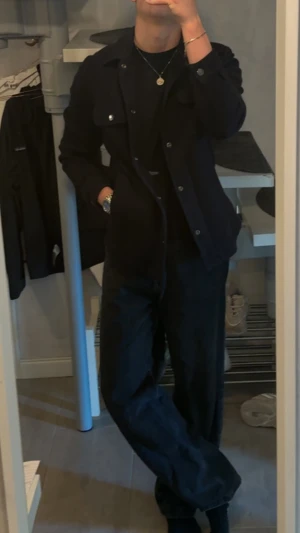 Mörkblå overshirt från BOSS - Säljer en stilren mörkblå overshirt från BOSS med klassisk krage, två bröstfickor med knappar och knappstängning framtill. Jackan är gjord i italiensk jersey med bi-stretch för extra komfort och har långa ärmar. Perfekt för dig som gillar clean och modern look.