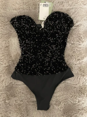 Glittrig svart body -  Supersnygg svart body från H&M i storlek XS med glittriga paljetter över hela överdelen. Bodyn är helt ny, med prislappen på. Helt slutsåld på hemsidan💕Skriv om ni har några frågor💕💕