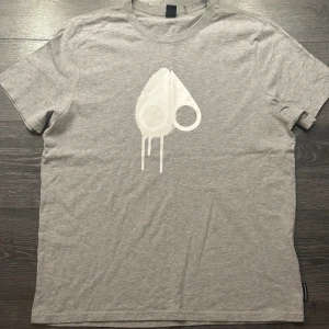 Moose Knuckles t-shirt  - Grå Moose Knuckles t-shirt i storlek XL säljer den då jag fick den i present men den är förstor. Köpt för 2000kr på Johnells. Aldrig använd så skicket är 10/10. Priset är diskuterbart o tveka inte på att skriva om ni har några frågor 