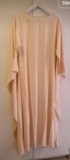 Laxrosa Abaya klänning  - Säljer en abaya med snygga volangdetaljer längs sidorna. Klänningen har en loose passform och är tillverkad i ett mjukt, lätt material som faller fint. Perfekt för dig som gillar en enkel men elegant look.