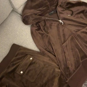 Brun Juicy Couture set - Säljer detta bruna juicy couture set i storlek M. Knappt använd då dessa var för stora för mig. Hela settet för 1000kr eller endast koftan eller byxorna för 500kr