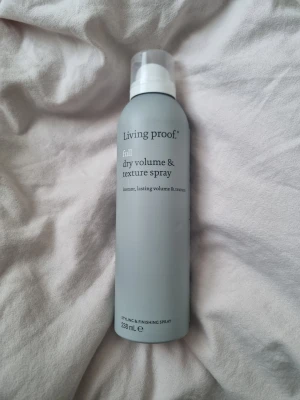 Living Proof Full Volume & Texture Spray - Living Proof Full Dry Volume & Texture Spray i en stilren grå flaska på 238 ml. Ger direkt volym och textur till håret med en lätt finish. Perfekt för att skapa en fylligare look och hålla frisyren på plats. Sprayen har en praktisk plastkork och är tillverkad i USA. Endast använd ett sprut in i locket av förpackningen, vilket man kan se.