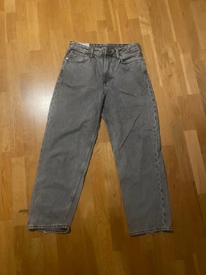 Grå loose fit byxor - Ljus grå jeans. Jeansen har en rå, fransad kant längst ner på benen som ger en cool och avslappnad vibe. Tillverkade i jeansmaterial med normal midja och raka ben. Perfekt för dig som gillar en enkel men trendig stil.