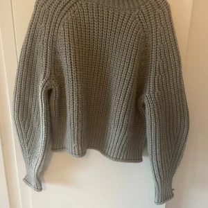 Grå stickad tröja från H&M - Säljer en chunky grå stickad tröja från H&M i storlek L. Tröjan har grov ribbstickning, rund hals och långa ärmar med breda muddar. Perfekt för att hålla sig varm och snygg under kyliga dagar. Enkel att styla med jeans eller kjol.