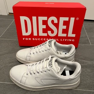 Diesel skor - Ett par stilrena vita, läder sneakers från märket Diesel. Nypris ca 2000kr, sparsamt använda endast lite smutsiga på sulan (bild 5). Hör gärna av er vid frågor!