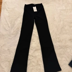 Svarta bootcut byxor från Bik Bok - Svarta bootcut byxor från Bik Bok i storlek M. Byxorna har en hög midja och är tillverkade i ett stretchigt material som sitter snyggt över höfterna och släpper ut över benen. Perfekta för en trendig och stilren look.