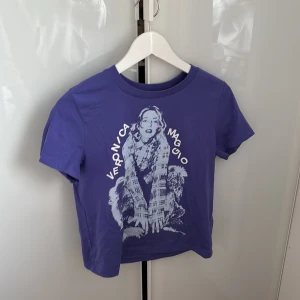 Lila Veronica Maggio t-shirt - Säljer en lila t-shirt med tryck av Veronica Maggio på framsidan. T-shirten har rund halsringning och korta ärmar. Materialet känns som bomull och trycket är i vitt. Perfekt för dig som gillar svensk pop! Andvänd endast 1 gång köpt på konsert sommaren 2024!