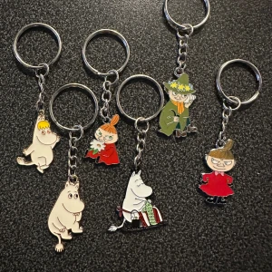 Nyckelringar med Muminmotiv 6 stycken nya - Säljer ett set med 6 nyckelringar med motiv från Mumindalen, inklusive Mumin, Snorkfröken, Lilla My och Snusmumriken. Figurerna är färgglada och tillverkade i metall med emaljerad yta. Perfekt för att ge din väska eller nycklar en personlig touch.