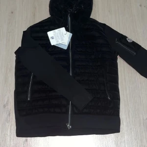 Svart Moncler pufferjacka med huva - Tja! Säljer en helt ny moncler cardigan i väldig fint skick. Kvaliteten känns premium, har aldrig använts och har inga defekter. OBS: bilderna kan se suddigt ut! 