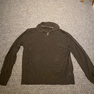 Mörkgrå half zip tröja Jack & Jones - Snygg mörkgrå långärmad tröja från Jack & Jones i storlek S. Tröjan har en krage med half zip-dragkedja och är tillverkad i mjukt stickat material. Perfekt för dig som gillar enkel och stilren design med lite extra edge i halsen.