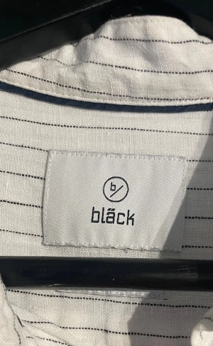 Vit randig skjorta från Bläck - Vit skjorta från Bläck med tunna svarta ränder och ståkrage. 