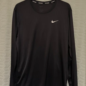  Nike Running Dri-Fit tröja - Svart långärmad Nike Running Dri-Fit träningströja, perfekt för löpning eller annan slags träning. Fint skick, men finns ett jättelitet hål vid ena axeln, som går rakt igen till andra sidan (se bild 5). Längd: ca 66cm, Bredd: ca 50cm