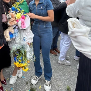 Blå denim jumpsuit med bootcut  - Snygg blå denim jumpsuit med kort ärm och klassisk skjortkrage. Byxorna har bootcut-snitt och hög midja som ger en riktigt schysst siluett. Perfekt för dig som gillar retrovibbar och vill sticka ut med en cool helhet.