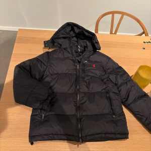 Svart pufferjacka från Ralph Lauren - Säljer en mycket snygg vinterjacka från Ralph lauren som är perfekt nu till vintern. Den är i mycket bra sick och har inga defekter, den är storlek XS men sitter mer som S. Nypris ungefär 4400kr, mitt pris: 2400kr. Postas samma dag som köp och pris är ej hugget i sten!