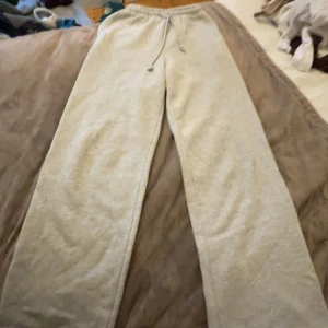 Grå mjukisbyxor med snörning - Grå mjukisbyxor med rak passform och elastisk midja med snörning. Tillverkade i mjukt bomullsmaterial, perfekta för chill dagar hemma eller när du vill vara extra bekväm. Färgen är ljusgrå och tyget har en enkel, klassisk look. Dem har en del fläckar som inte försvinner och därför säljer jag dem väldigt billigt