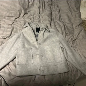 Ljusgrå overshirt från 157. - Snygg ljusgrå overshirt från 157, stora framfickor och knäppning med knappar. Jackan har en stilren, boxig passform och är fodrad med slätt tyg. Perfekt för lager-på-lager och enkel att matcha med jeans eller sneakers.