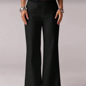 Svarta bootcut kostymbyxor med fickor - Snygga svarta bootcut kostymbyxor med klassisk passform och fickor bak. Byxorna har hög midja och vida ben som ger en cool siluett. Perfekta att matcha med crop tops eller stickade tröjor. Materialet känns mjukt och följsamt mot huden.