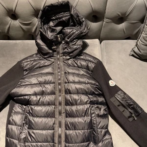 Svart Moncler pufferjacka med huva - Moncler cardigan använd ett par gånger 4-6 gånger.Den passar folk med storlek L väldigt bra,jag som har storlek S/M sitter den lite lös på mig därför så säljer jag den för den är lös på mig eftersom det är storlek L