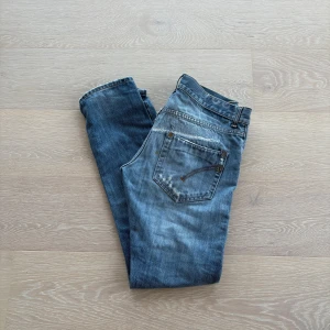 Dondup Jeans - Säljer ett par dondup jeans i blå tvätt med coola slitningar och detaljer på både fram- och baksida. Perfekt för dig som gillar en avslappnad streetstil.