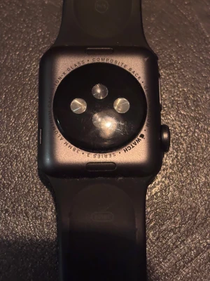 Apple Watch Series 3 38mm svart - Apple Watch Series 3 med 38mm aluminiumboett i svart och matchande svart silikonarmband. Klockan har en stilren, fyrkantig design med digital krona och pulsmätare på baksidan. Perfekt för dig som gillar teknik och vill ha koll på din vardag direkt på handleden.