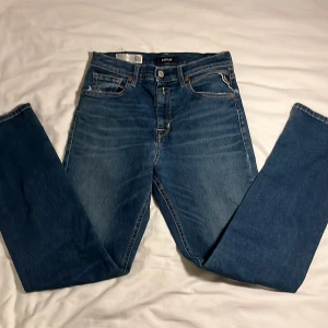 Blå Replay jeans straight fit - Snygga blå jeans från Replay med klassisk femficksdesign och raka ben. Jeansen har ljusa tvättade detaljer och kontrastsömmar, samt Replay-logga på linningen. Perfekt passform med normal midja och robust jeansmaterial.
