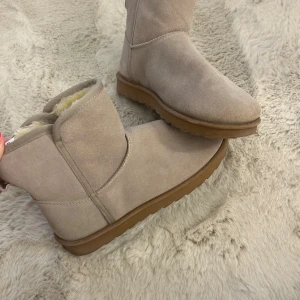 Beige uggs från Linear of Sweden - Mysiga beige uggs från Linear of Sweden med mjukt foder på insidan. Utsidan är i mocka och de har en platt sula i brunt gummi. Köpte förra vinter säsongen, men passar inte riktigt mig i storleken så de blev aldrig använda! 
