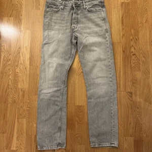 Grå jeans från Jack & Jones, storlek 30/32 - Snygga grå jeans från Jack & Jones med klassisk femficksdesign och raka ben. Jeansen har en cool tvättad look och är tillverkade i mjukt bomullsmaterial. Passar dig som gillar en enkel och stilren vibe.
