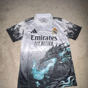 Real Madrid draktröja Adidas S - Säljer en unik Real Madrid fotbollströja från Adidas med coolt drakmotiv i svart och turkos på framsidan. (Ny med prislapp)