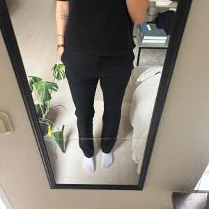 Svarta kostymbyxor från H&M, strl 40 - Snygga svarta kostymbyxor från H&M i storlek 40. Byxorna har rak passform med normal midja och klassisk look. Perfekta för dig som gillar stilrena och enkla plagg. Materialet är mjukt och följsamt, vilket gör dem bekväma att bära hela dagen.