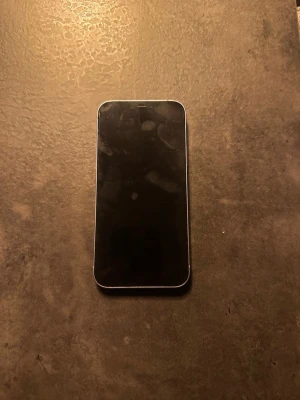 iPhone 12 - Snygg lila iPhone 12 med dubbla kameror och platt design. Skärmen har inga synliga sprickor. Baksidan och kanterna ser fina ut utan större slitage. Perfekt för dig som vill ha en modern och kraftfull smartphone med 128 GB.