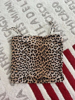 Leopardmönstrad linnetopp Gina Tricot - Säljer en leopardmönstrad linnetopp från Gina Tricot i storlek S. Toppen har tunna axelband och är i mjukt, stretchigt material. Färgerna går i beige, svart och brunt och mönstret är riktigt snyggt och trendigt.