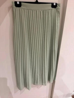 Ljusgrön plisserad långkjol från AWARE - Säljer en superfin ljusgrön långkjol från AWARE i storlek XS. Kjolen är plisserad med elastisk midja för skön passform och har en flowy look. Perfekt till sneakers eller sandaler för en chill vibe.