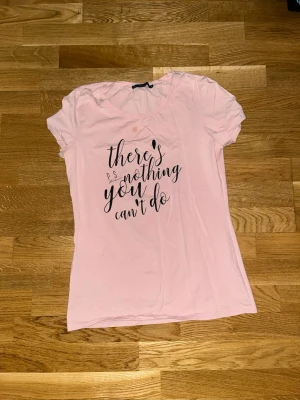Ljusrosa t-shirt från P.S. Sation - Säljer en ljusrosa t-shirt från P.S. Sation med svart texttryck på framsidan: 'there's nothing you can't do'. T-shirten har rund halsringning och korta ärmar. Tillverkad i mjuk bomull för en bekväm känsla. Only problem a oil stain that is not able to leave 