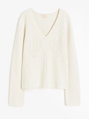 Vit ribbad stickad tröja med v-ringning - Snygg vit stickad tröja med ribbad struktur och djup v-ringning. Tröjan har långa ärmar och ett diskret mönster framtill som ger en cool touch. Perfekt att styla med jeans eller kjol för en fräsch look. Aldrig används därför är den helt ny. Nypris är 550kr.