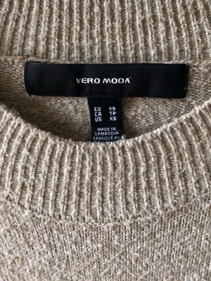 Beige stickad tröja från Vero Moda - Mysig beige stickad tröja från Vero Moda i storlek XS. Tröjan har rund halsringning, långa ärmar och ribbade muddar vid hals, ärmslut och nederkant. Perfekt för lager på lager under kyliga dagar. Den ser nopprigare ut en vad den är då den nästan inte e använd 